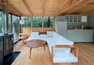 sauanaga aiamaja puhkeruumi sisevaade, valge diivan, pruun diivanilaud ja roheline köök